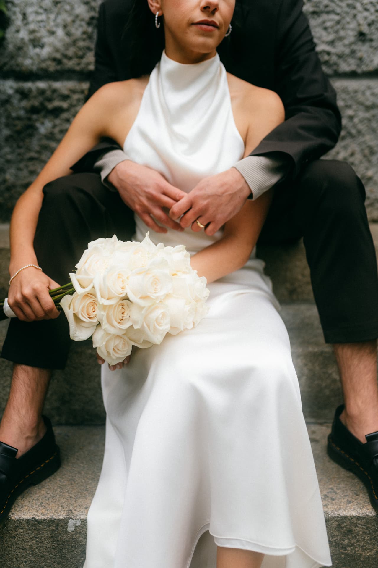 Braut mit weißem Rosenstrauß auf Steintreppe – editorial Hochzeitsfotografie