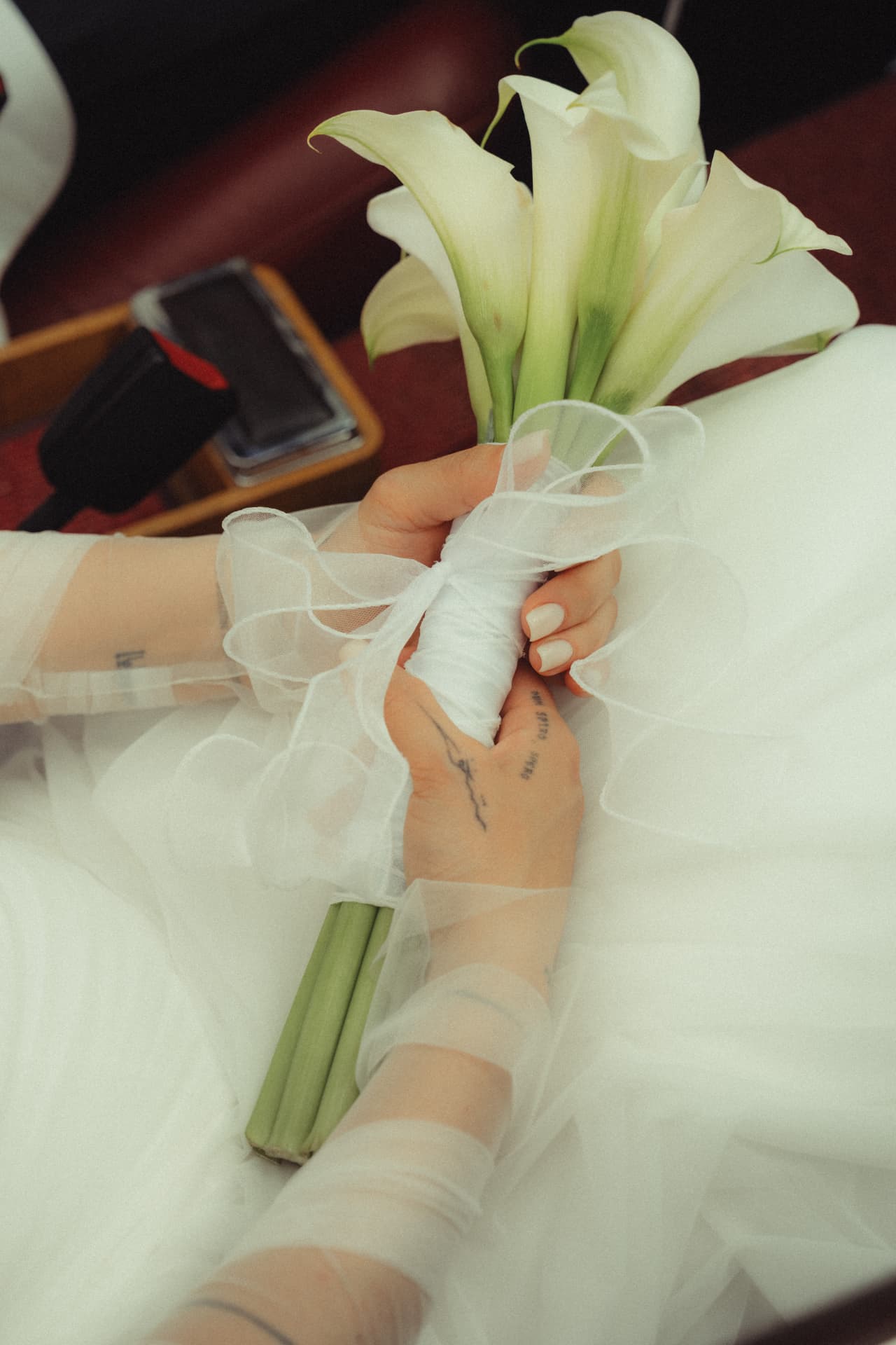 Detail Braut hält Callas-Brautstrauß in transparenten Handschuhen – Hochzeitsdetail