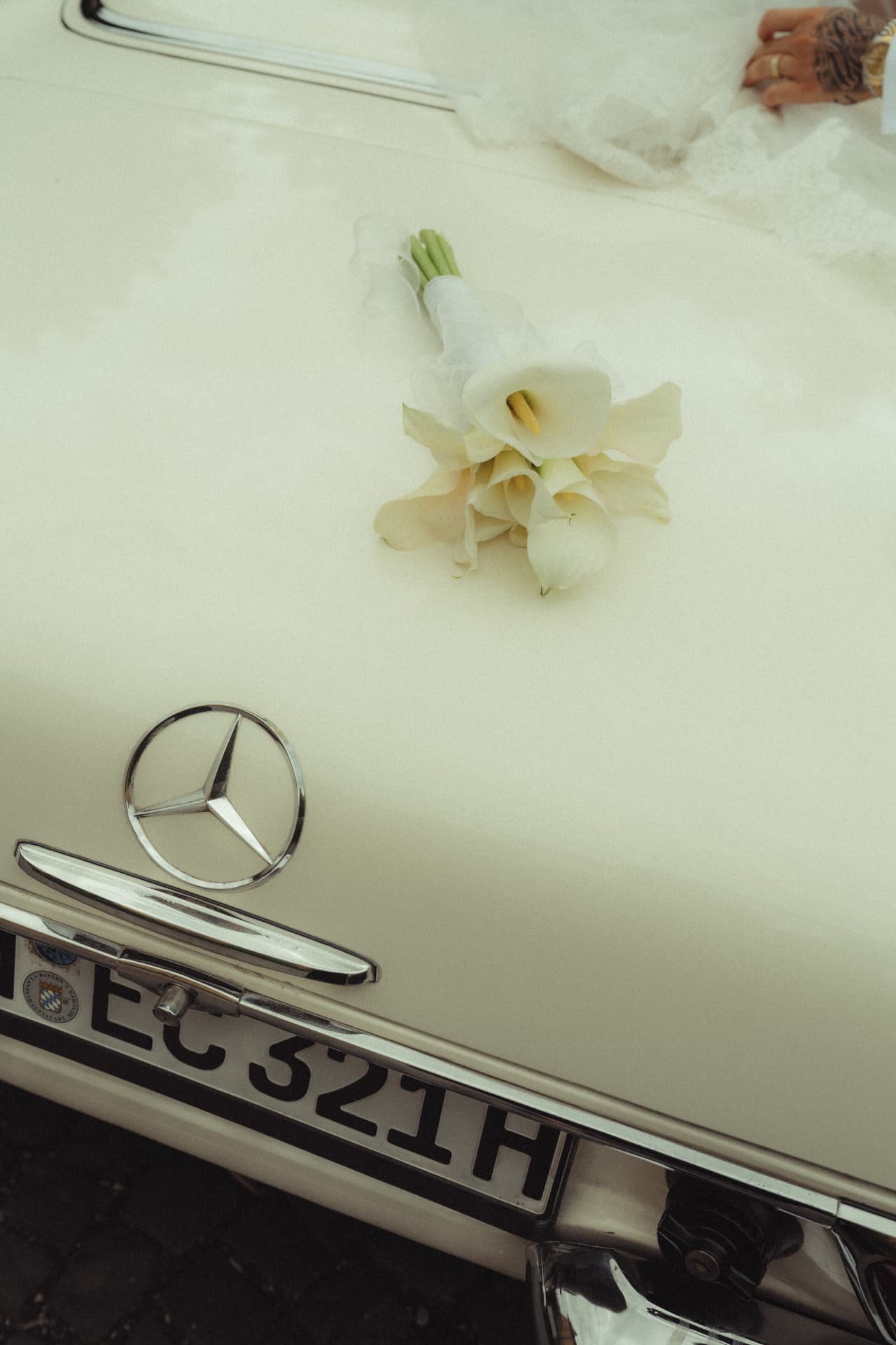Callas-Brautstrauß auf Motorhaube weißer Mercedes Oldtimer – editorial Hochzeitsdetail