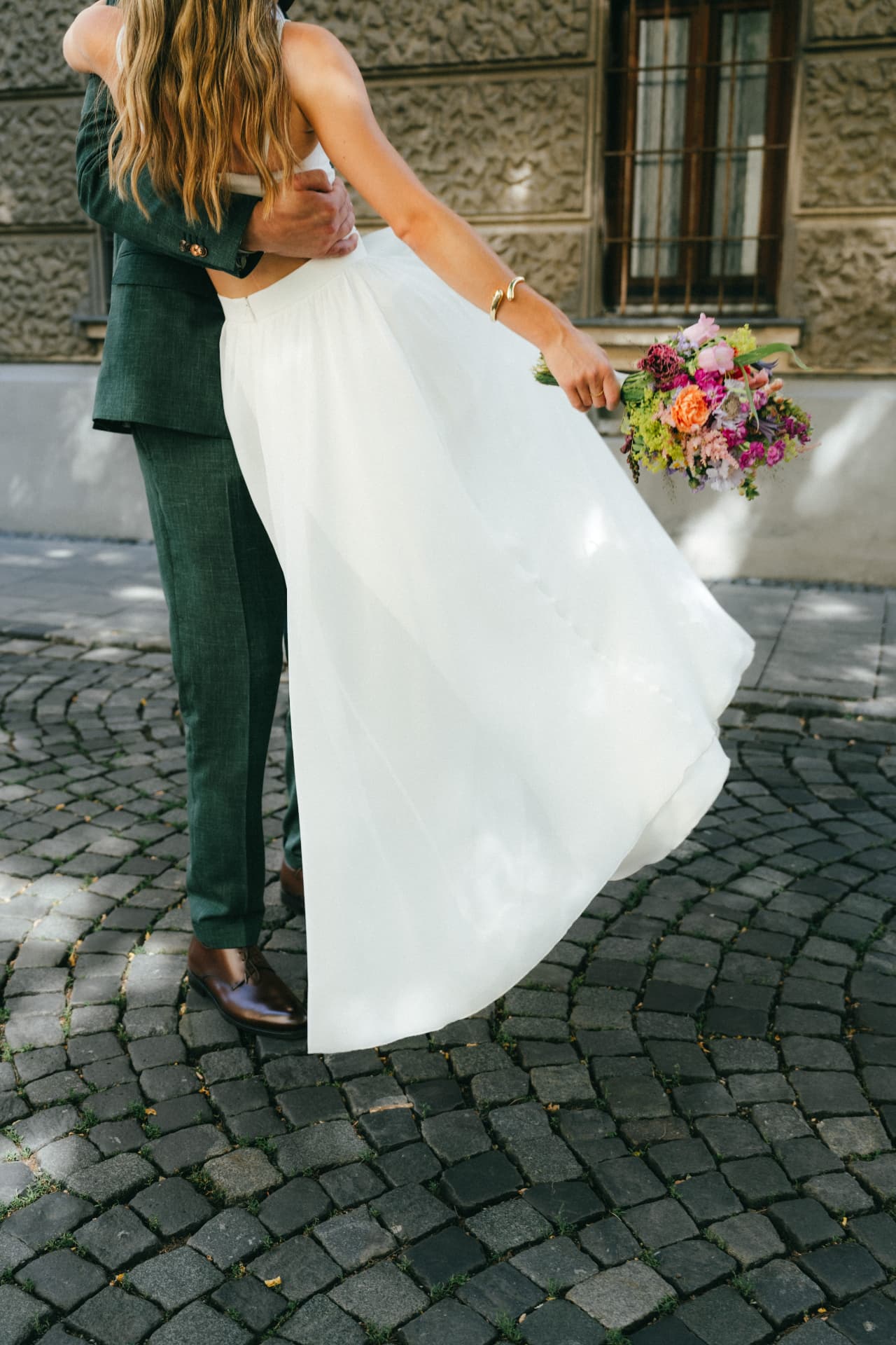 Braut mit fließendem Kleid und Bräutigam auf Kopfsteinpflaster – Hochzeitsfotograf Augsburg
