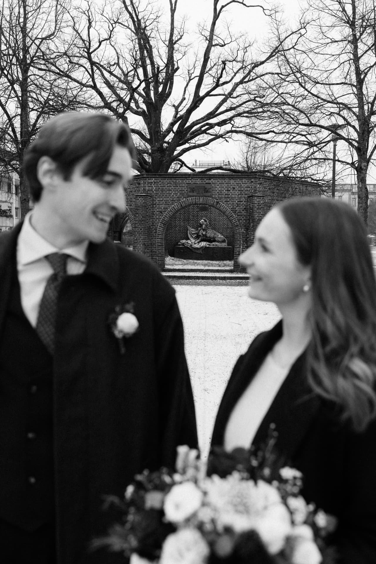 Brautpaar lächelt sich im Winter im Park an – standesamtliche Hochzeit Schwarzweiß