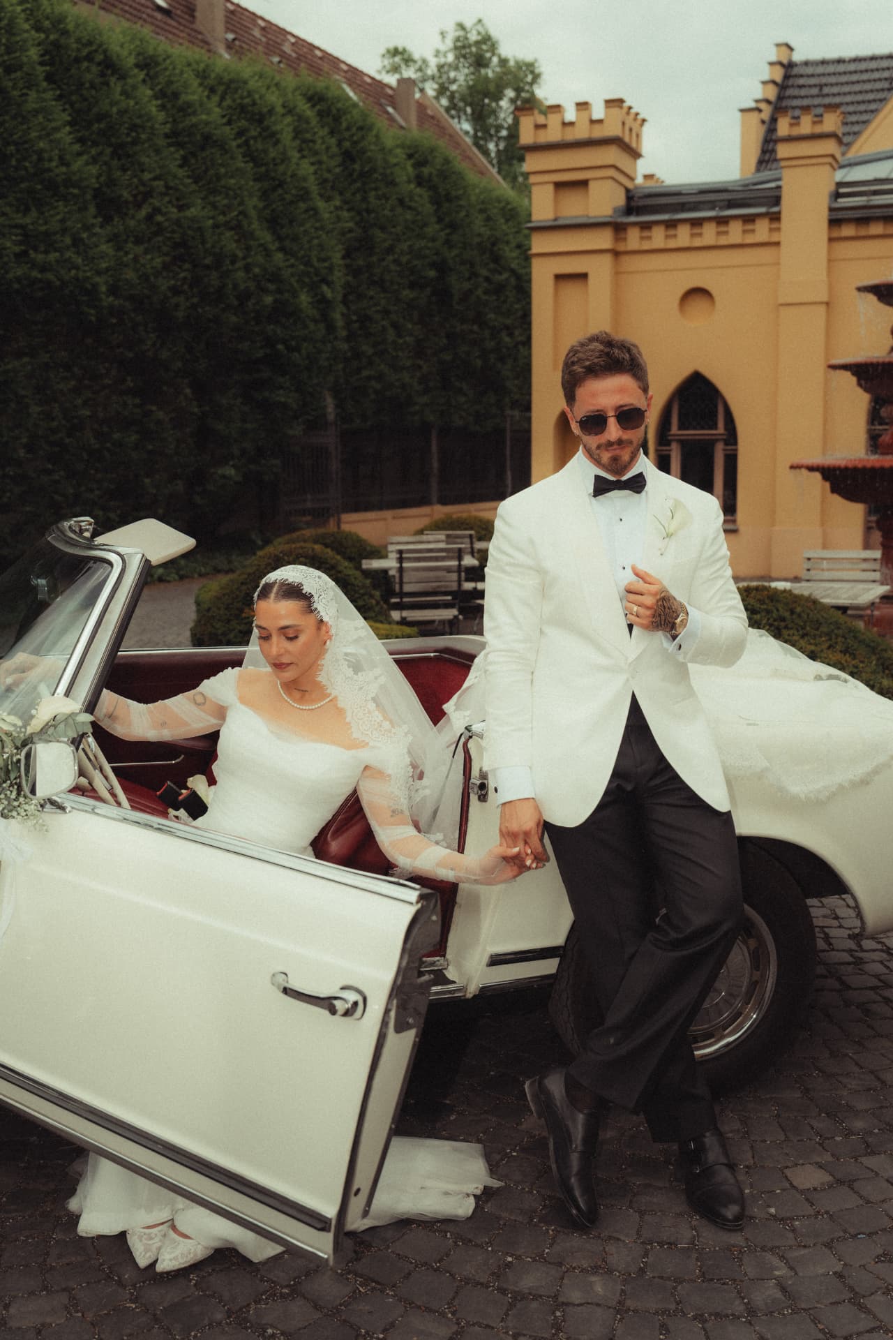Brautpaar am weißen Oldtimer vor Schloss – luxuriöse Hochzeitsreportage