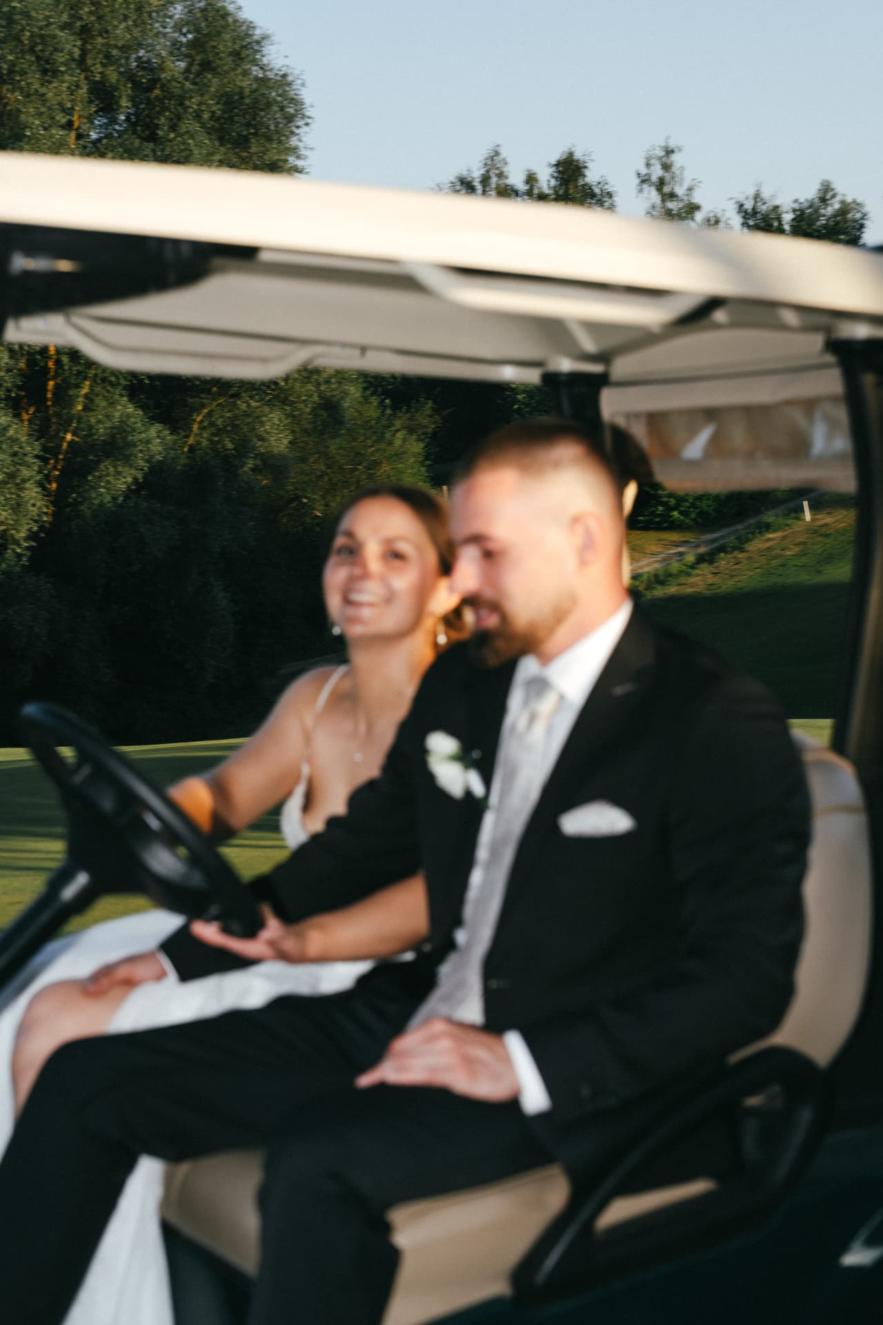 Brautpaar lacht bei der Fahrt im Golfcart – ungestellte Hochzeitsreportage Bayern